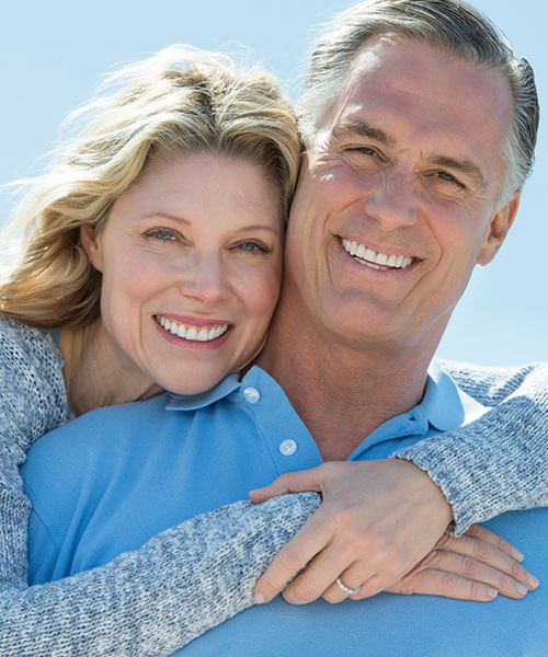 An older woman hugging her husband and smiling